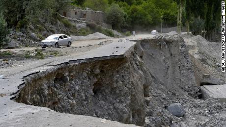 A car passes through a partially collapsed section of the Karakoram Expressway in Pakistan that was damaged after a glacial lake exploded in the country's Gilgit-Baltistan region.