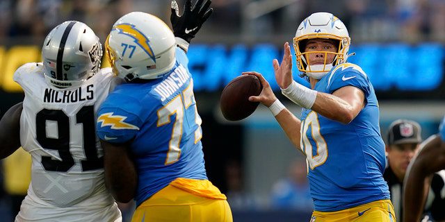 Los Angeles Chargers quarterback Justin Herbert, right, passes against the Las Vegas Raiders to defend Bilal Nichols, No. 91, applying pressure during the second half of an NFL football game in Englewood, California, Sunday, September 11, 2022.