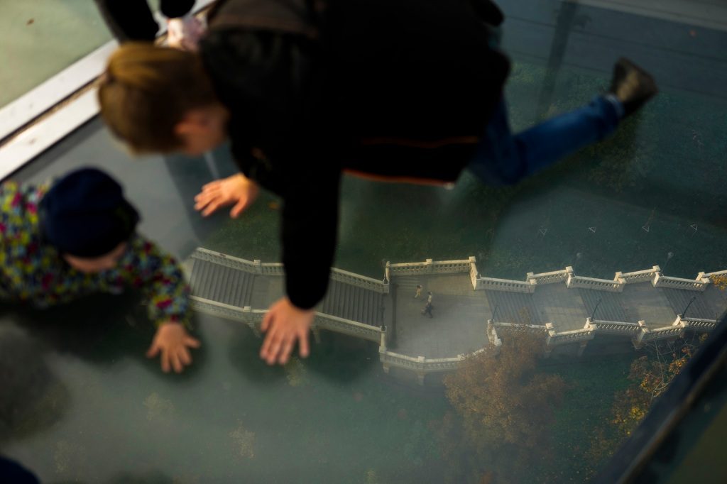 Two children looking through the glass floor of the bridge